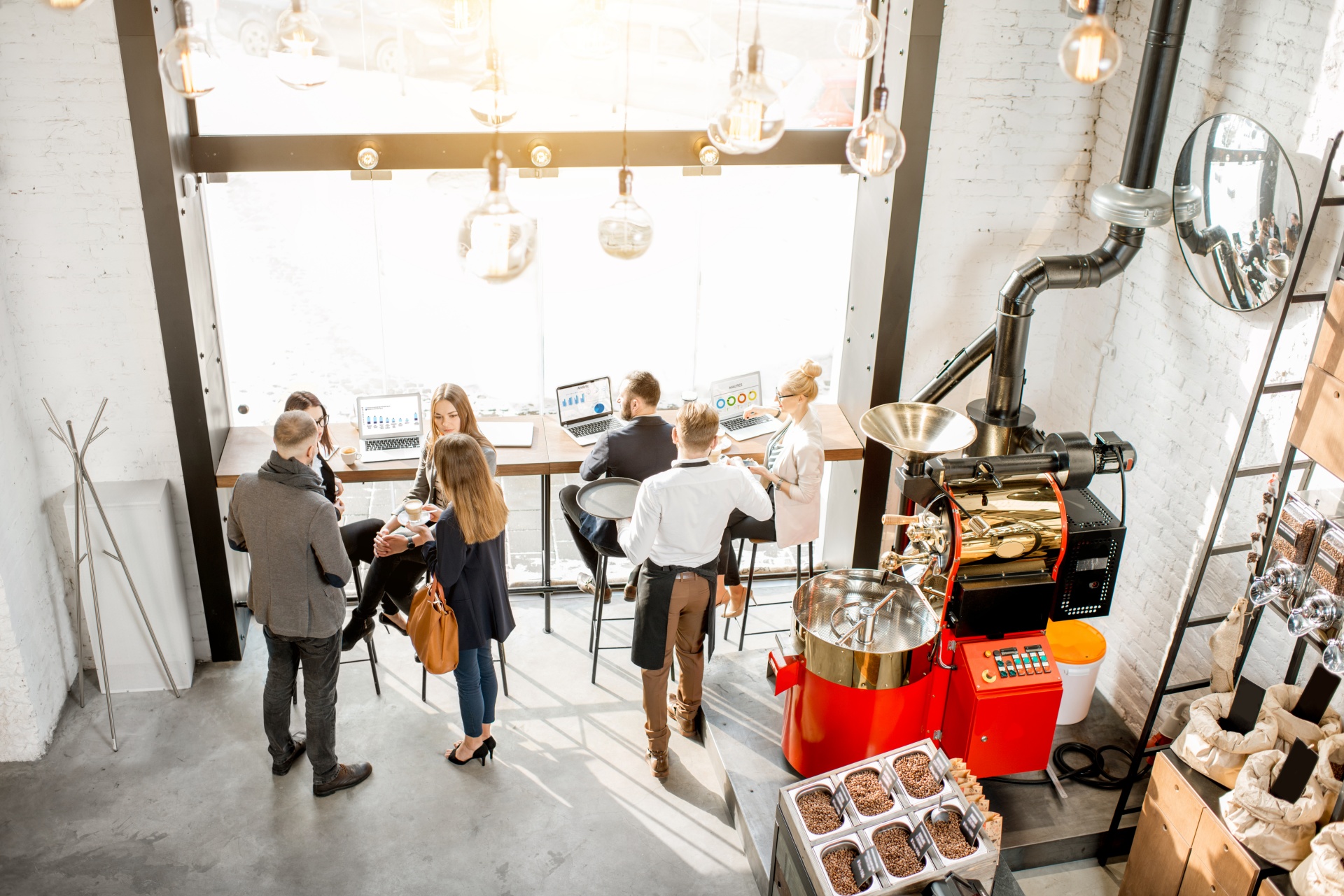 Top view on the cafe interior with business people having a conversation durnig a coffee time sitting with laptops near the window