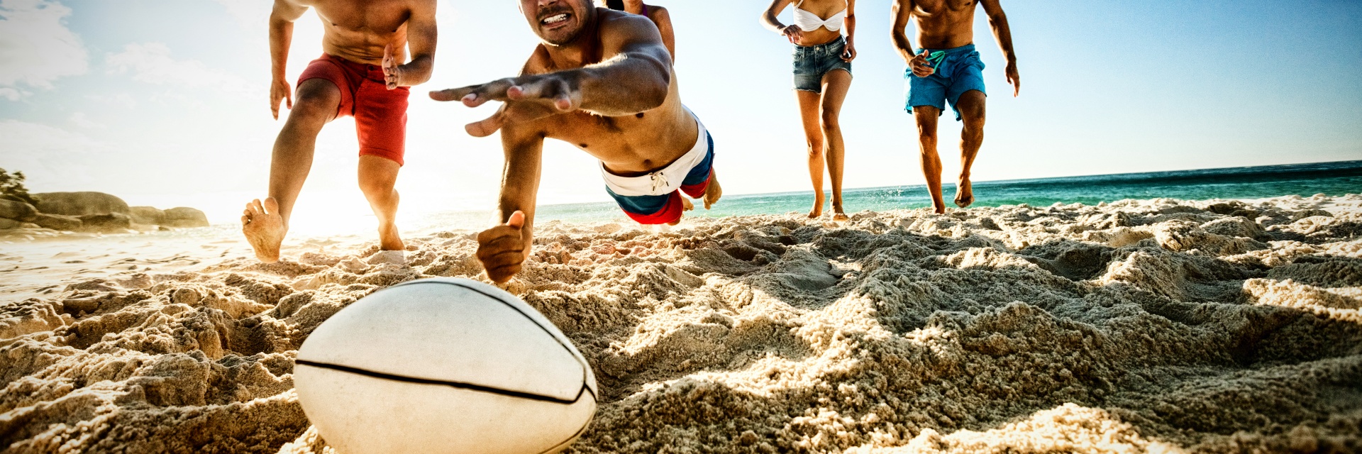 Friends playing rugby at the beach